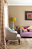 Striped armchair and curtains with coir matting in living room of Sussex home England UK