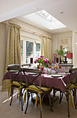 Square table with purple tablecloth in sunlit kitchen of Sussex home England UK