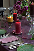 Purple and green place setting with lit candles on Sussex dining table England UK