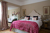 Pink cover on double bed in room with wooden floorboards Sussex England UK