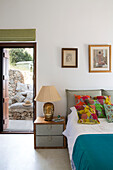 Bedside lamp with colourful cushions and open door from bedroom in Ithaca villa Greece
