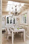 Chandelier and Christmas decorations hang above white dining table in South London England UK