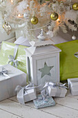 Star shaped lantern with gift wrapped presents under Christmas tree in South London family home England UK