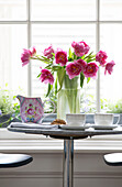 Pink Peonies (Paeonia) on table in window of London townhouse England UK