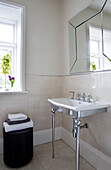 Folded towels on stool with washbasin and mirror in Worcestershire bathroom England UK