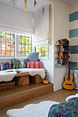 Guitar and dollshouse with split level window seat with fur throw in London home England UK