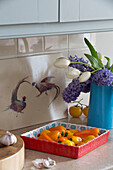 Hyacinth (Hyacinthus) and tulips with peppers and garlic and artwork of fighting pheasants in Kelso kitchen Scotland UK