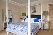 White four poster bed and large mirror with cork floor in Gloucestershire home England UK