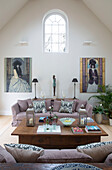 Arched window in double height living room wall with portraits living room conversion in Gloucestershire farmhouse England UK