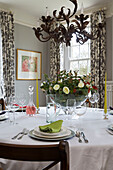 Lime green napkin on place setting below metal chandelier in Gloucestershire farmhouse England UK