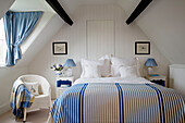 Striped duvet with co-ordinated gingham fabrics in attic bedroom of Gloucestershire farmhouse England UK