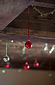 Red and silver baubles hang from timber-framed ceiling in Hampshire farmhouse England UK