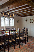 Lit candelabra above dining table with polished chairs at Christmas in timber-framed Hampshire farmhouse England UK