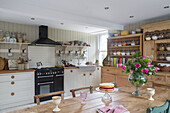 Viktoriabiskuit auf Kuchenständer mit rosa Rosen in Bauernhausküche Midlothian Schottland UK