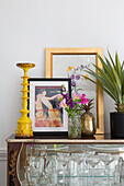 Framed prints and yellow candlestick with houseplant on display cabinet in Brighouse home West Yorkshire UK
