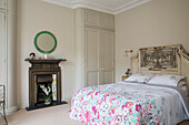 Floral duvet on bed with antique headboard in London townhouse UK