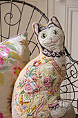 Cat cushion on metal chair in London townhouse bedroom UK