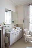 Doppelwaschbecken mit Spiegelschrank und Korbsessel im Badezimmer eines Londoner Stadthauses UK