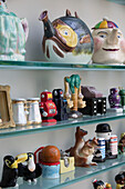 Collection of novelty kitchenware on glass shelves in London townhouse UK