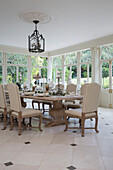 Cream dining chairs at table in tiled Kent conservatory England UK