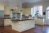 Marble-topped island unit with parquet floor in cream fitted kitchen of Kent country house England UK