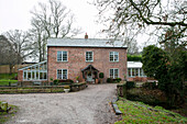 Gravel driveway approach to detached brick Cheshire farmhouse UK