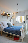 Weihnachtsgeschenke und Strümpfe mit blauer Decke auf weißem Bett mit Metallrahmen in einem Haus in Cheshire, Großbritannien