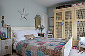 Patchwork quilt on double bed with with cream wardrobe in Cheshire home UK