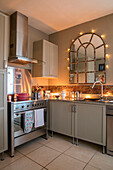 Lichter um einen gewölbten Spiegel mit einem Ofen aus Edelstahl in einer Küche in Cheshire UK