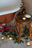 Lit tealights and berries with leaves on wooden bathroom stool in Berkshire home UK