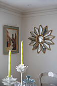 Sunburst mirror and artwork with candles in West Sussex home