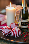 Lit candle and striped baubles with glass and bottle in farmhouse on Wiltshire Dorset borders UK