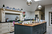 Silver pendant lights above teal workbench in Dorset farmhouse kitchen UK