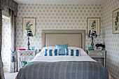 Blue striped pillows with matching lamps and patterned wallpaper in Dorset farmhouse UK