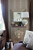 Gold metallic lamp and mirror on chest of drawers in detached Sussex country house UK