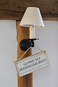 Notice of absence hangs on wall sconce in Oast house conversion Kent UK