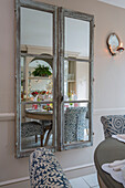 Salved French doors reflect chairs and table in dining room of London townhouse UK