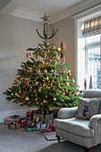 Christmas tree with gifts and armchair in window of 1890s Victorian villa Liverpool