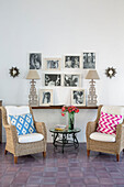 Family photographs above shelf with pair of wicker chairs in Italian villa on the Amalfi coast