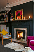 Sessel am Kamin mit Kerzen auf dem Kaminsims in der Wohnung in Hove, East Sussex, Großbritannien