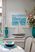 Model boat and nautical artwork with place setting on dining table in Victorian terraced house South London UK