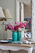 Cut flowers in turquoise vase with mirror on console in Victorian terrace house South London UK