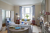 Pair of lamps with light blue curtains at bay window in living room of Victorian terrace house South London UK