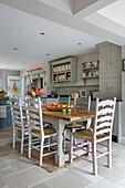 Painted chairs at table in fitted kitchen with plate rack in Alford home Surrey UK