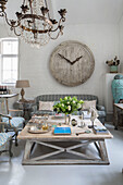 Large wooden clock face with low table and sofa in whitewashed South London schoolhouse conversion UK