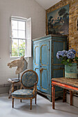 Antique chair with storage cupboard and horses head at window in South London schoolhouse conversion UK