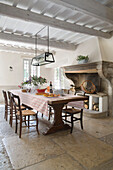 Moderner Glaslampenschirm über dem Esstisch mit originalem Kamin in einem provenzalischen Bauernhaus aus dem 19