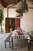 Große Pendelleuchten aus Korbgeflecht hängen über dem Esstisch auf der Außenterrasse eines provenzalischen Bauernhauses aus dem 19