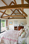 Schlafzimmer mit hoher Balkendecke und eigenem Bad in einer umgebauten Scheune in Gloucestershire UK