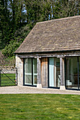 Terrassentüren und Ziegeldach außen an einer umgebauten Scheune in Gloucestershire, Großbritannien